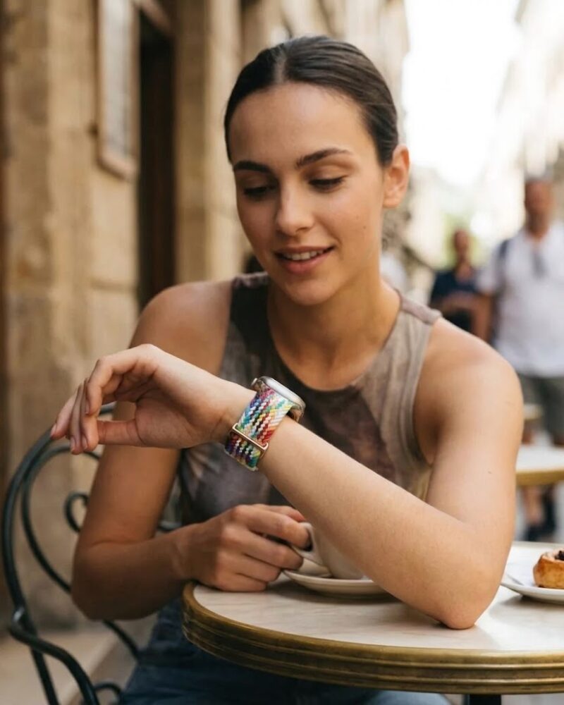 Woman wearing colorful braided loop Apple Watch band with rainbow pattern design